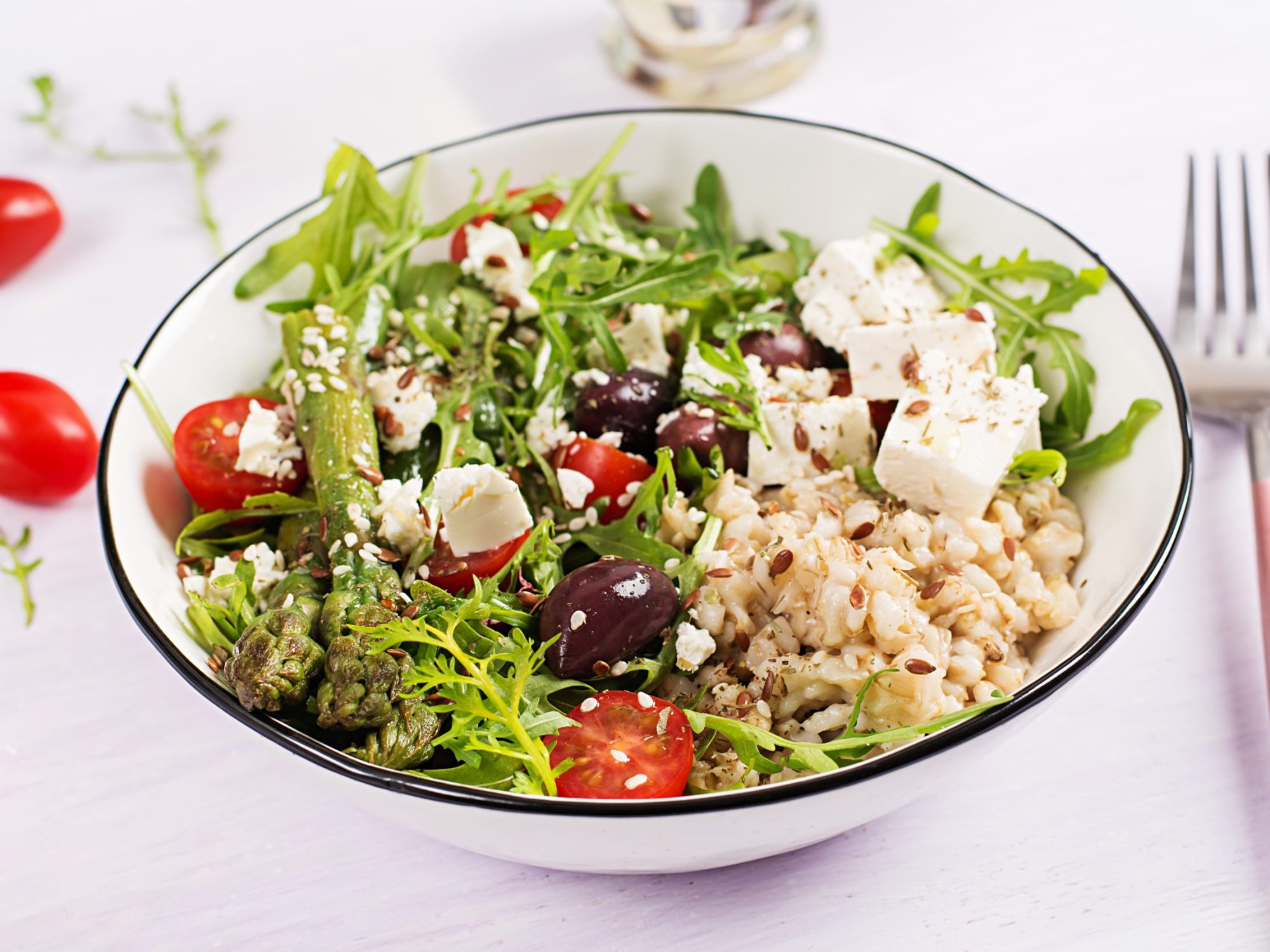 Breakfast oatmeal porridge with feta cheese, cherry tomatoes, asparagus and arugula. Healthy balanced food.